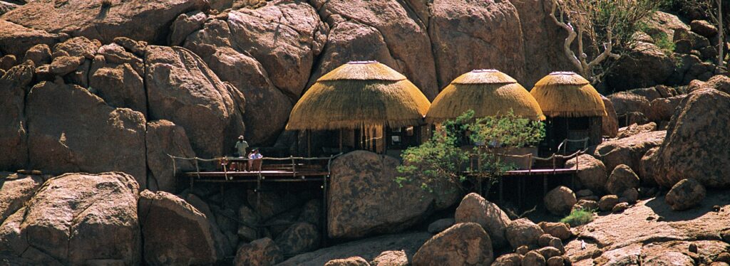 Namibian huts with straw roofs set amoungst rocks in the desert.